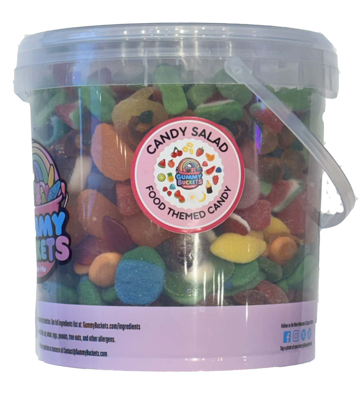 A clear plastic bucket filled with assorted colorful candy salad, featuring a round pink label that reads 'CANDY SALAD FOOD THEMED CANDY' and a visible 'Nummy Secrets' logo on the left side. The bucket has a clear lid and a clear handle, set against a plain white background.