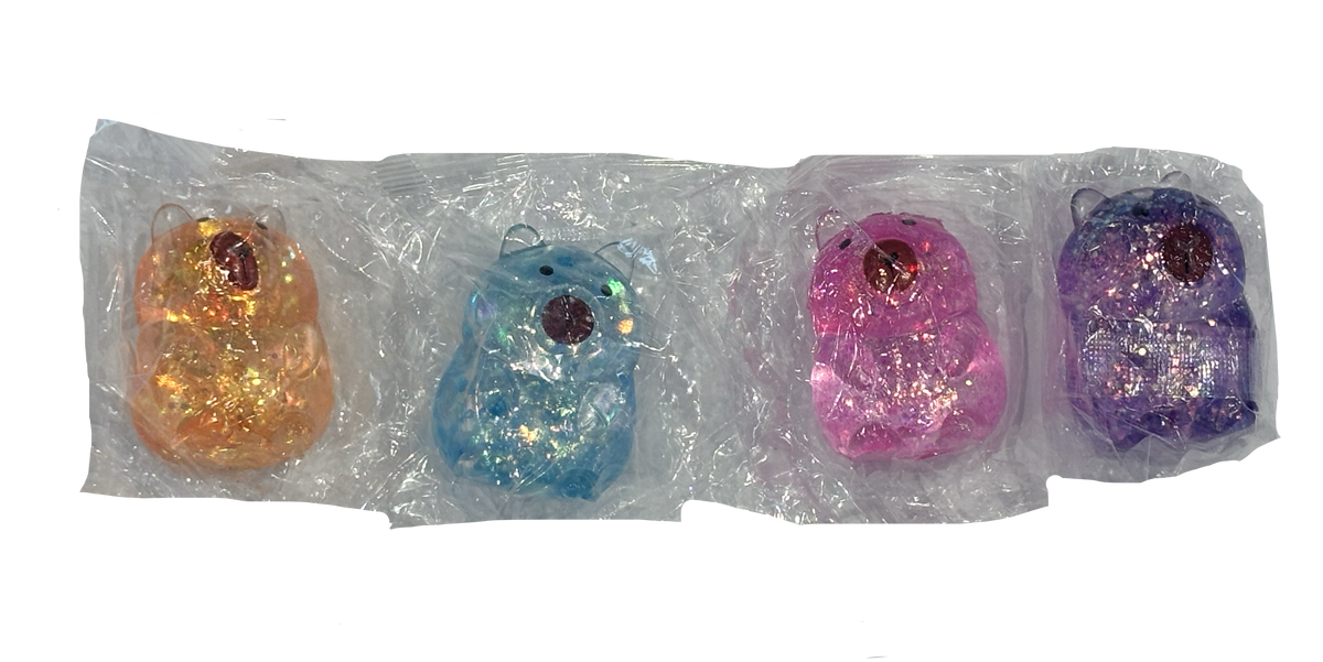 Four small glittery bear-shaped items in different colors, each individually wrapped in clear plastic packaging, arranged in a row against a white background. Orange/brown, blue, pink and purple glittery options.