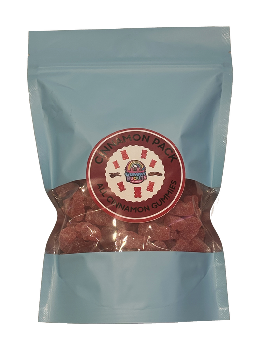 A light blue resealable stand-up pouch of candy gummies with a clear window showing reddish-brown cinnamon pack gummies inside. A round red and white label on the front reads 'CINNAMON PACK' and 'ALL CINNAMON GUMMIES' with a small logo in the center.
