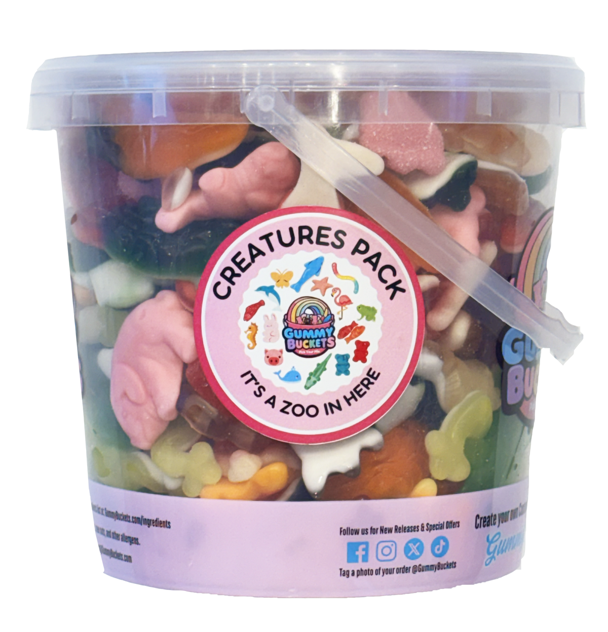 A clear plastic bucket filled with assorted colorful gummy candies, featuring a round pink and white 'Creatures Pack' label on the front. The bucket has a translucent lid, a clear plastic scoop inside, and a light pink lower band with social media details.