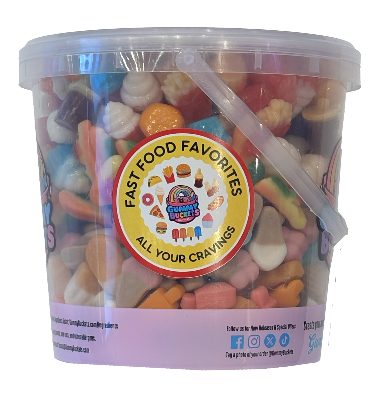 A clear plastic tub filled with assorted colorful candy pieces, featuring a large circular 'Crazy Cakes' label on the front. The tub has a translucent lid, a clear side handle, and a light purple bottom band with social media details.