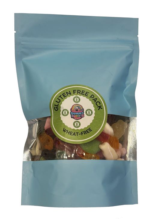 A light blue resealable stand-up pouch with a clear window showing a colorful assortment of mixed gummy candies including bears, worms, peach rings, and fruit shapes inside. A round green label on the front reads 'GLUTEN FREE PACK' and 'WHEAT-FREE' with the Gummy Buckets logo surrounded by illustrated wheat-free and gluten-free certification icons in the center.