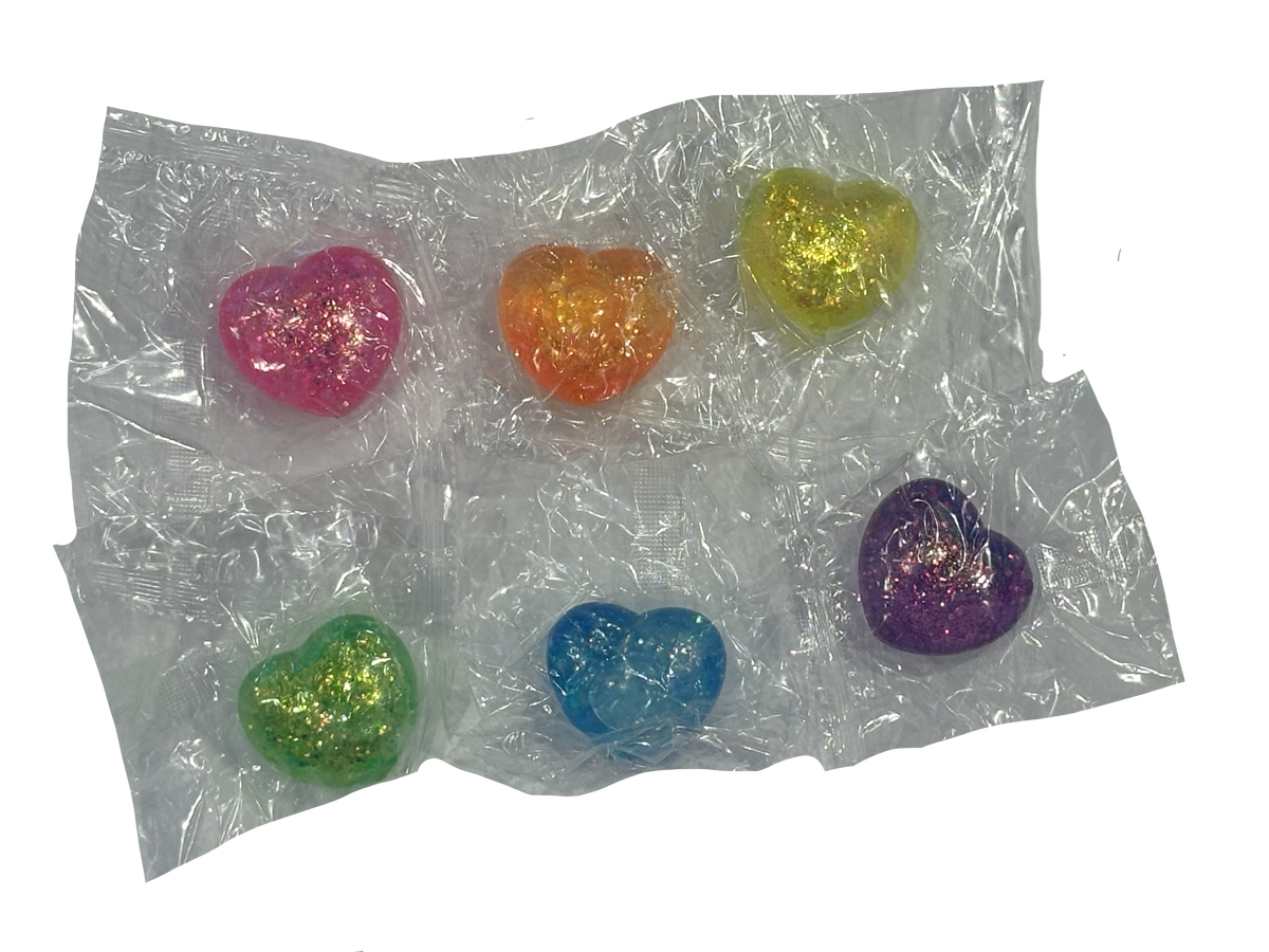 Six small heart-shaped glitter charms in pink, orange, yellow, green, blue, and purple, packaged in a clear plastic blister pack on a white background.