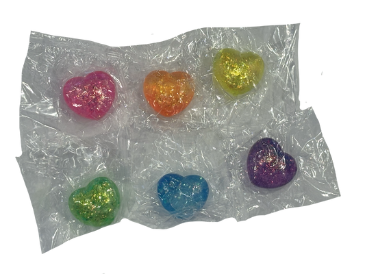 Six small heart-shaped glitter charms in pink, orange, yellow, green, blue, and purple, packaged in a clear plastic blister pack on a white background.
