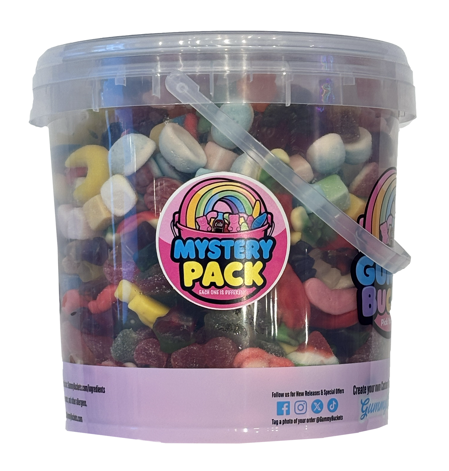 A clear plastic bucket filled with assorted gummy candies and marshmallows, featuring a large circular 'Mystery Pack' label with a rainbow graphic on the front. The bucket has a translucent lid, a clear plastic handle, and a light purple base band with social media details.
