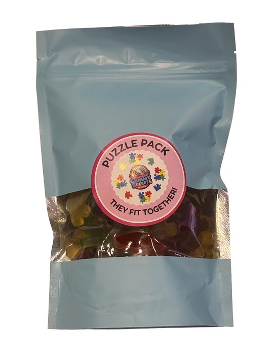 A light blue resealable stand-up pouch containing a mix of colorful gummy candies visible through a clear window, with a round pink label reading 'PUZZLE PACK' and 'THEY FIT TOGETHER!'.