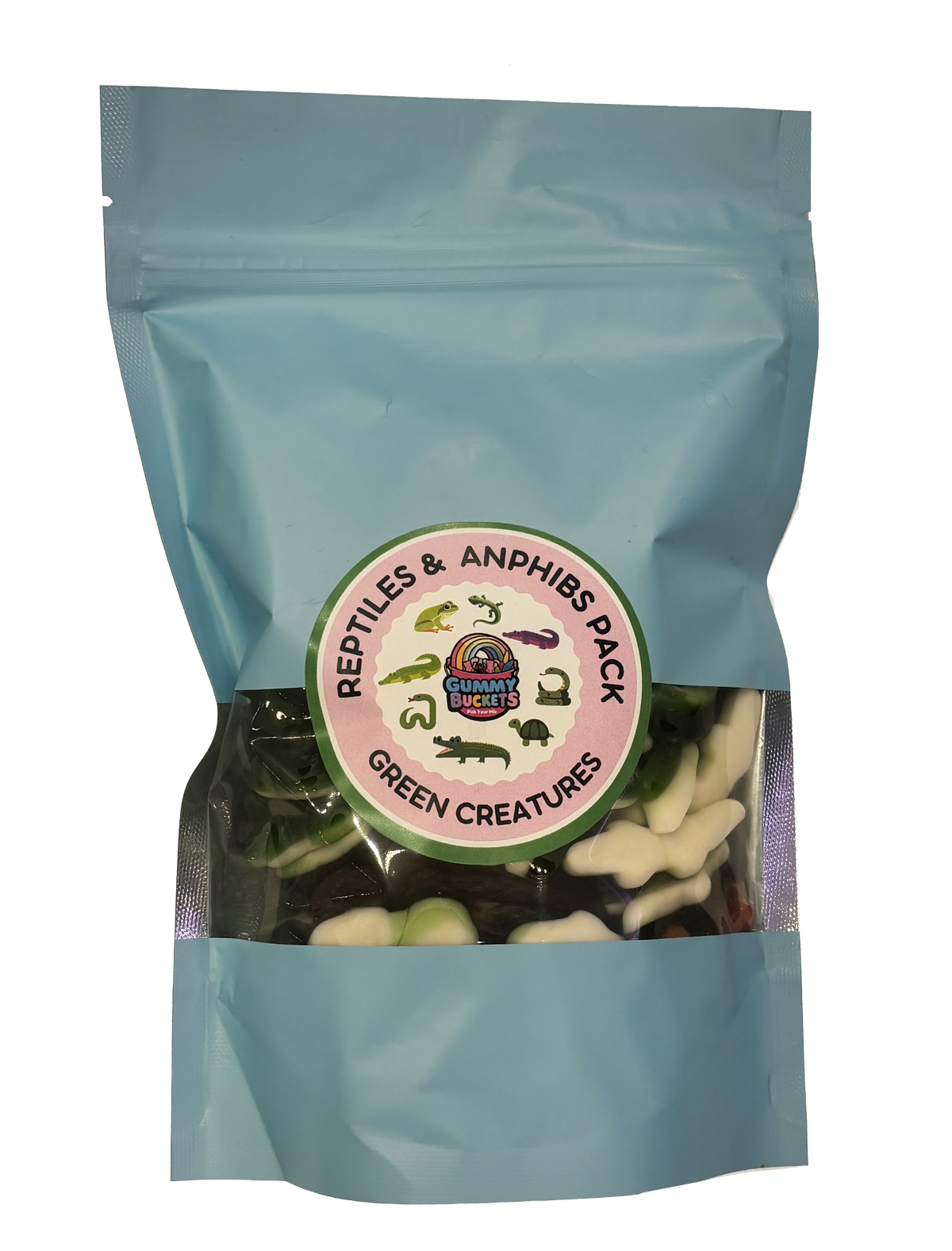 A light blue resealable stand-up pouch with a clear window showing green and white reptile and amphibian-shaped gummy candies including frogs, alligators, snakes, and turtles inside. A round green and pink label on the front reads 'REPTILES & AMPHIBS PACK' and 'GREEN CREATURES' with the Gummy Buckets logo surrounded by illustrated reptile silhouettes in the center.
