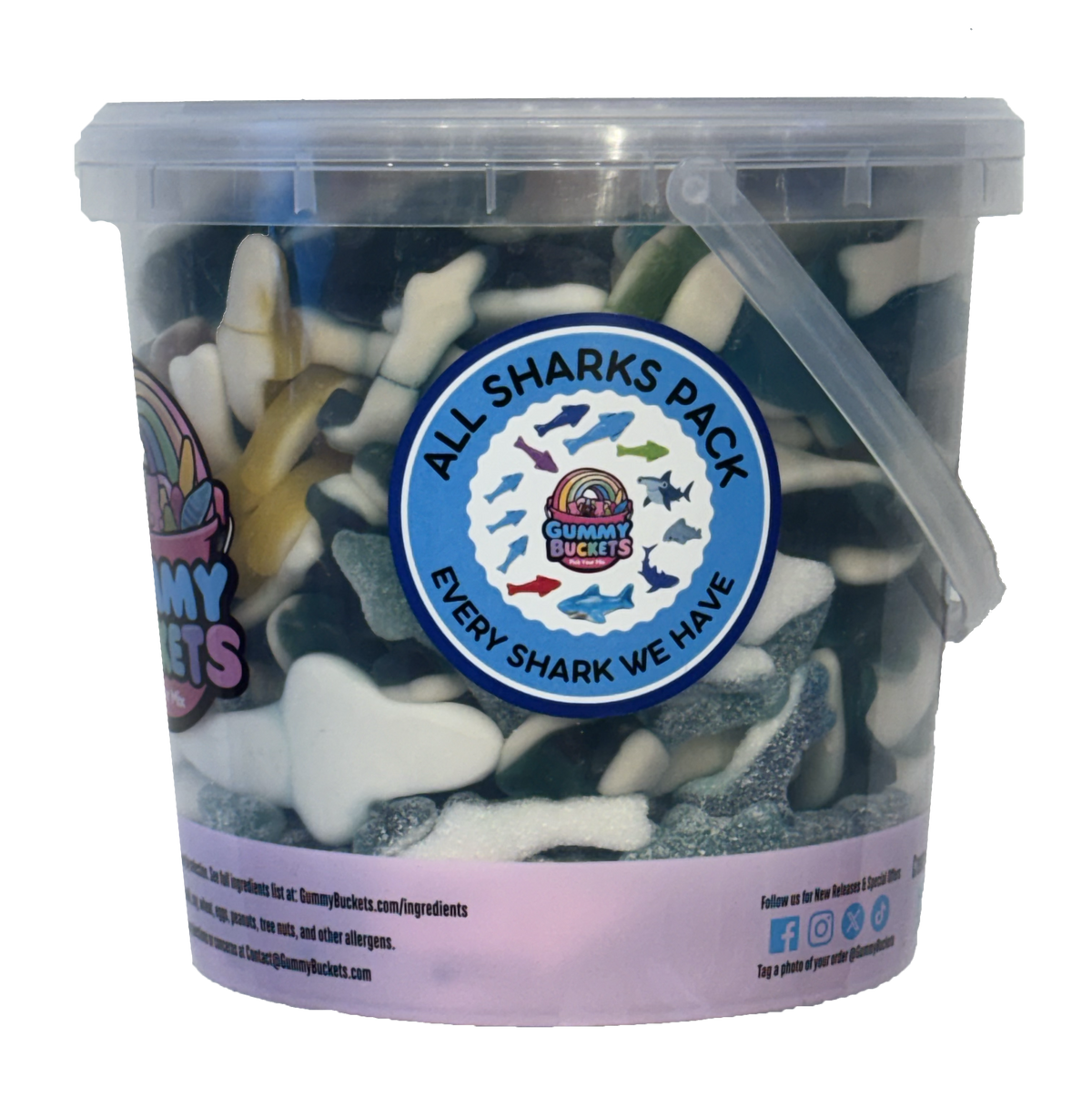 A clear plastic tub filled with assorted shark-shaped gummy candies, featuring a large blue circular label that reads 'ALL SHARKS PACK' and 'EVERY SHARK WE HAVE'. The tub has a translucent lid and handle, with a light purple paper band around the lower portion.