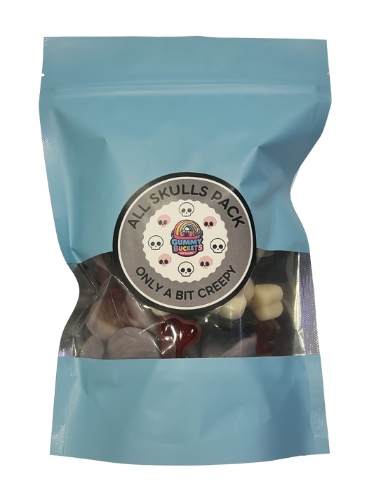 A light blue resealable stand-up pouch with a clear window showing black, red, and white skull-shaped gummy candies inside. A round dark gray label on the front reads 'ALL SKULLS PACK' and 'ONLY A BIT CREEPY' with the Gummy Buckets logo surrounded by illustrated skull icons in the center.