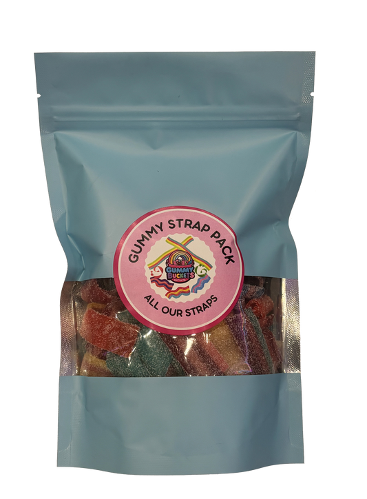 A light blue resealable stand-up pouch with a large clear window showing a colorful assortment of flat gummy strap candies in red, orange, blue, and green inside. A round pink label on the front reads 'GUMMY STRAP PACK' and 'ALL OUR STRAPS' with the Gummy Buckets logo surrounded by illustrated colorful crossed strap candy icons in the center