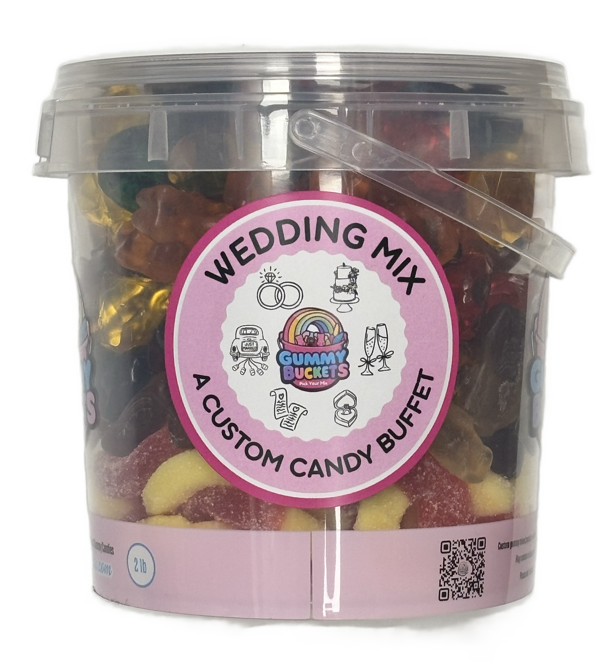 A clear plastic bucket filled with assorted gummy candies and wrapped sweets, labeled 'WEDDING MIX' and 'A CUSTOM CANDY BUFFET' by Gummy Buckets. The bucket has a pink circular label and a transparent lid with a handle.