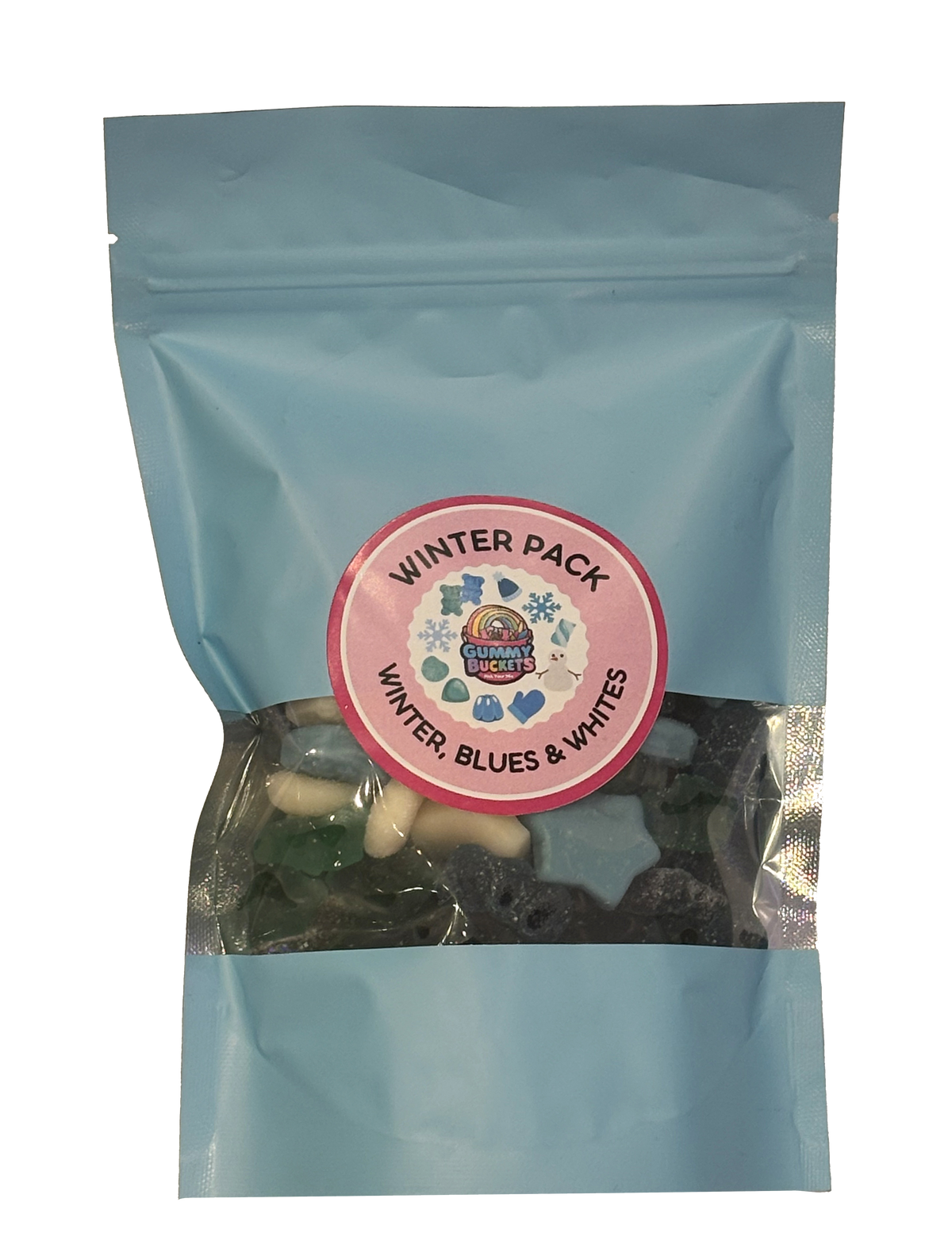 A light blue resealable stand-up pouch photographed on a marble countertop with a clear window showing blue, white, and silver winter-themed gummy candies including snowflake shapes, white bears, and sugared blue gummies inside. A round pink label on the front reads 'WINTER PACK' and 'WINTER, BLUES & WHITES' with the Gummy Buckets logo surrounded by illustrated snowflake and winter candy icons.
