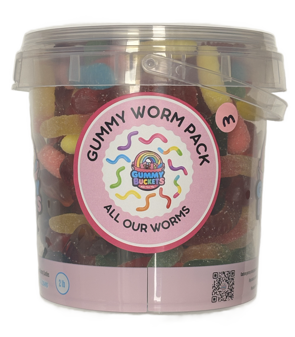 A clear plastic bucket filled with assorted gummy worms and gummy candies, featuring a pink circular label that reads 'Gummy Worm Pack' and 'All Our Worms' with the Gummy Buckets logo. A small pink circle on the bucket indicates a 3-pack.